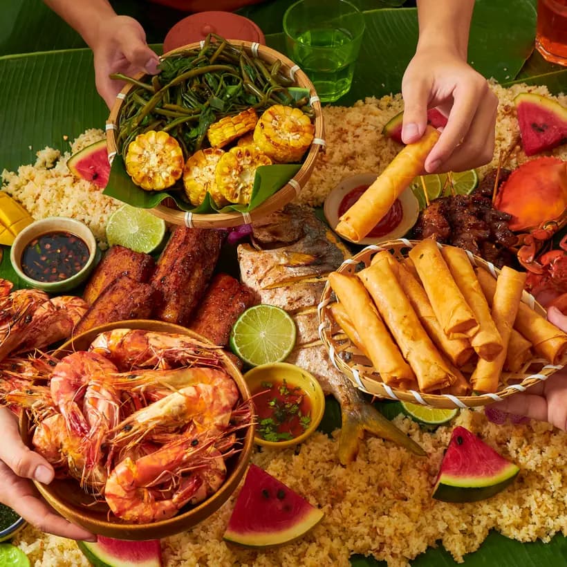 Overhead shot of a shared seafood feast with prawns, spring rolls, grilled fish and rice at a Malaysian restaurant